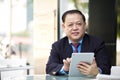 Senior Asian businessman using tablet PC