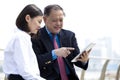 Senior Asian businessman and young female Asian executive using tablet PC Royalty Free Stock Photo