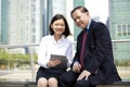 Senior Asian businessman and young female Asian executive using tablet PC