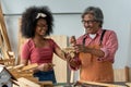 Senior Asian carpenter teaching a girl to work with wood in carpentry shop