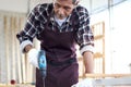 Senior Asian carpenter work in woodwork workshop, old citizen craftsman working with hand drill in the joinery, cheerful elderly Royalty Free Stock Photo