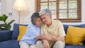 Senior asian couple comforting each other from depressed emotion while sitting on sofa at home living room, old retirement Royalty Free Stock Photo