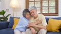 Senior asian couple comforting each other from depressed emotion while sitting on sofa at home living room, old retirement