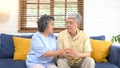 Senior asian couple comforting each other from depressed emotion while sitting on sofa at home living room, old retirement