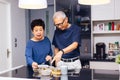 Senior Asian couple grandparents cooking together while woman is feeding food to man at the kitchen. Long lasting relationship Royalty Free Stock Photo