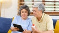 Senior asian couple holding bottle of pill using digital tablet to make video conference call to doctor, pharmacy consulting about Royalty Free Stock Photo