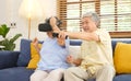 Senior asian couple playing virtual reality headset and using digital tablet in home living room with happiness emotion, Royalty Free Stock Photo