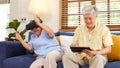 Senior asian couple playing virtual reality headset and using digital tablet in home living room with happiness emotion, Royalty Free Stock Photo