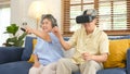 Senior asian couple playing virtual reality headset and using digital tablet in home living room with happiness emotion, Royalty Free Stock Photo