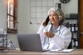 Senior asian female doctor using mobile phone talking while sitting in hospital office. happy woman medical worker Royalty Free Stock Photo