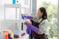 Senior Asian housekeeper cleaning at the clean living room and her hands in waist watching the bookshelf beside the sunlight Royalty Free Stock Photo