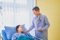 Senior asian male doctor visiting and talking with middle-aged female patient on Ward. Royalty Free Stock Photo