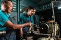 Senior Asian male master craftsman, teaching assistant to turn steel with hand tools, carefully in a small factory Royalty Free Stock Photo