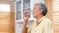 Senior asian man drinking water while standing by window in kitchen background, elderly retirement people and healthy lifestyles Royalty Free Stock Photo
