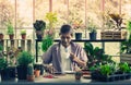 Senior Asian man having morning coffee while reading digital tablet in his houseplant garden at home Royalty Free Stock Photo