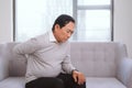 Senior asian man with pain in back sitting on sofa Royalty Free Stock Photo