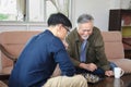 Senior Asian man playing chess with his son in the living room for elder and family concept