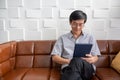 Senior Asian man playing tablet on sofa in living room at home  Portrait of Asian elderly man is Relaxing and Happiness With Royalty Free Stock Photo