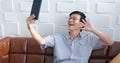 Senior Asian man playing tablet and video call on sofa in living room at home  Portrait of Asian elderly man is Relaxing and Royalty Free Stock Photo