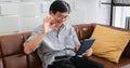 Senior Asian man playing tablet and video call on sofa in living room at home  Portrait of Asian elderly man is Relaxing and Royalty Free Stock Photo