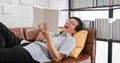 Senior Asian man reading book and Laughing on sofa in living room at home  Portrait of Asian elderly man is Relaxing and Happiness Royalty Free Stock Photo