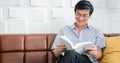 Senior Asian man reading book on sofa in living room at home ,Portrait of Asian elderly man is Relaxing and Happiness With Read a Royalty Free Stock Photo