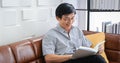 Senior Asian man reading book on sofa in living room at home ,Portrait of Asian elderly man is Relaxing and Happiness With Read a Royalty Free Stock Photo