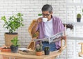 A senior Asian man sitting and drink coffee and reading the newspaper with happiness. Idea for relaxing and slowly life of older Royalty Free Stock Photo