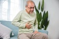 Senior Asian man sitting on sofa having suffering from stomach ache holding his stomach pain Royalty Free Stock Photo