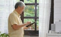 Senior asian man using digital tablet computer at home background, Retirement asian man and digital tablet standing by home window Royalty Free Stock Photo