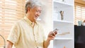 Senior asian man using smartphone at home background, Happy retirement asia male holding phone while standing in kitchen, Active