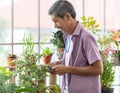 A senior Asian man working in a planting hobby room with happiness. Idea for green lover who plants tree and botany in corner of Royalty Free Stock Photo