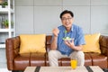 Senior Asian men sitting on the sofa at home while eating green vegetable salad and organic orange juice for breakfast. Healthy Royalty Free Stock Photo