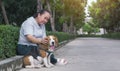 Senior Asian woman gently stroking her beagle dog while resting on walkway in public park Royalty Free Stock Photo