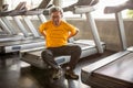 Senior asian sport man injury back pain  sitting on treadmill in fitness gym . elder male exercising , workout, training ,healthy Royalty Free Stock Photo