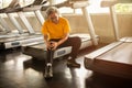 Senior asian sport man injury knee pain  sitting on treadmill in fitness gym . aged  suffering from Arthritis elder male Royalty Free Stock Photo