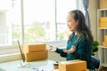 Senior Asian woman doing online shopping at home with boxes and laptop Royalty Free Stock Photo