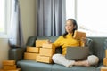 Senior Asian woman doing online shopping at home with boxes and laptop Royalty Free Stock Photo