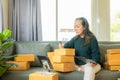 Senior Asian woman doing online shopping at home with boxes and laptop Royalty Free Stock Photo