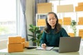 Senior Asian woman doing online shopping at home with boxes and laptop Royalty Free Stock Photo