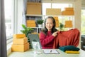 Senior Asian woman doing online shopping at home with boxes and laptop Royalty Free Stock Photo