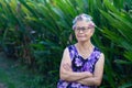 Senior Asian woman hair curlers and arms crossed while standing in a garden Royalty Free Stock Photo