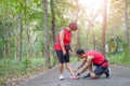 Senior asian woman with man or personal trainer tying shoe laces in the park