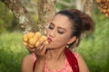 The senior Asian woman pose is eating longkong fruits under longkong tree in the garden with happiness.