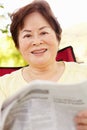 Senior Asian woman reading outdoors Royalty Free Stock Photo