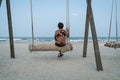 Senior Asian woman relaxing on a wood plank swing on the beach Royalty Free Stock Photo