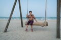 Senior Asian woman relaxing on a wood plank swing on the beach Royalty Free Stock Photo