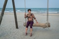 Senior Asian woman relaxing on a wood plank swing on the beach Royalty Free Stock Photo