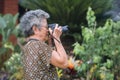 Senior Asian woman shooting photo by digital camera. Elderly Asian woman with short white hair, wearing eyeglasses, happy when Royalty Free Stock Photo