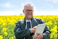 Senior attractive farmer working in a field helped by his tablet